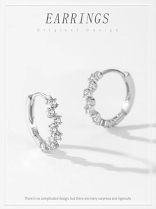 Macro detail of S925 sterling silver huggie earrings with wavy cubic zirconia stones