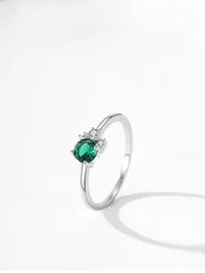 Detail of S925 silver ring featuring round green emerald zircon and side white accents