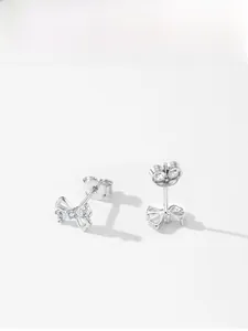 Detailed view of silver bow-shaped stud earrings with three central sparkling zircons