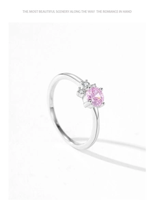 Macro shot of pink zircon ring with silver band and side stones on white background