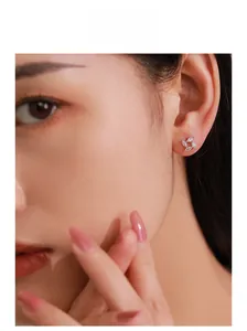 Close-up of S925 silver windmill stud earrings with sparkling zircon stones on model