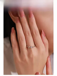 Gros plan d'une bague en argent rose doré avec trois fleurs en zircone sur une main