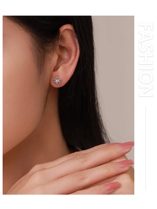 Close-up of S925 sterling silver hollow flower stud earring worn by a female model