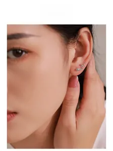 Détail macro du clou d'oreille serpent en argent avec yeux en pierre verte sur modèle