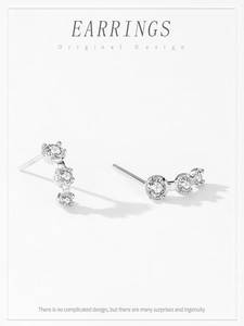 Detailed macro view of S925 sterling silver curved earrings with three bright cubic zirconias