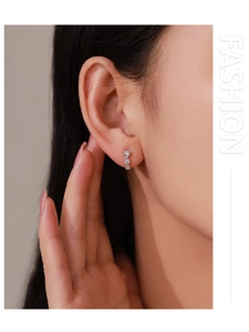 Macro detail of silver stud earrings featuring three vertically set sparkling zircons