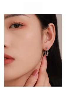 Gros plan d'un mannequin portant des boucles d'oreilles en argent 925 avec diamants