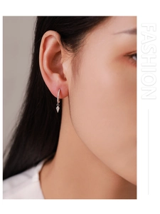 Close-up of a woman wearing silver geometric diamond-encrusted drop earrings