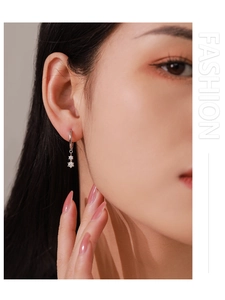 Macro shot of 925 silver hoop earrings with shimmering star zircon pendants on ear