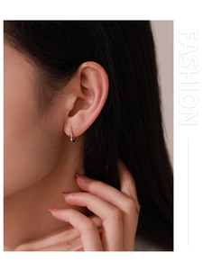 Close-up of minimalist S925 sterling silver hoop earring worn on woman's earlobe