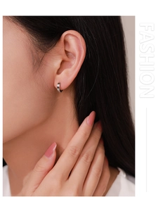 Détail de la boucle d'oreille créole en argent S925 avec zircons incrustés sur l'oreille