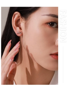 Detailed view of S925 silver bowknot stud earrings with tiny diamonds on model's ear