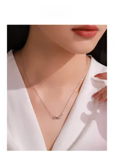 Detailed view of S925 silver necklace with sparkling knotted bow pendant on model