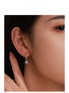 Macro view of sterling silver flower drop earring with sparkling zircon on model ear