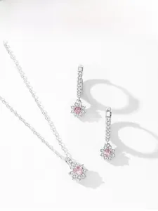 Detail view of pink flower jewelry set including silver pendant necklace and earrings