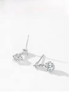 Detailed macro view of asymmetric 925 silver flower and geometric cube stud earrings