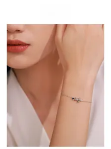 Detail of S925 sterling silver kitten bracelet with blue zircon on a woman's wrist
