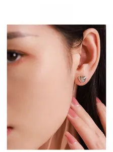 Close-up of heart-shaped silver stud earring with starburst stone on model ear