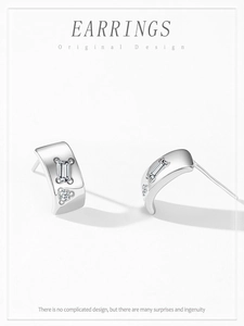 Detail of 925 silver C-shaped earrings featuring baguette and round-cut cubic zirconia stones