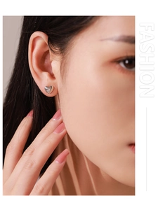Close-up of 925 sterling silver heart earrings with starburst zircon on female earlobe