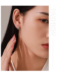 Close-up of geometric C-shaped 925 silver earrings with zircon stones on a model