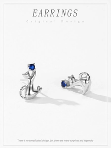Macro shot of S925 sterling silver cat earrings with deep blue round gemstone settings
