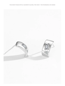 Macro shot of 925 silver C-shape stud earrings with square and round zircon stones