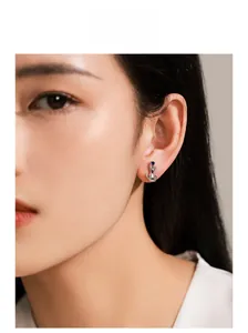 Close-up of S925 silver cat stud earring with a blue gemstone on female model ear