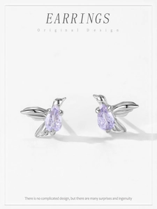 Macro detail of silver hummingbird earrings with purple pear-shaped zirconia stones