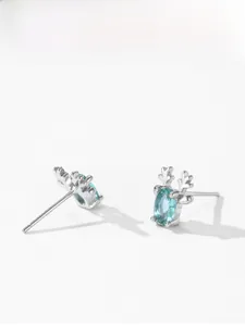 Détail de boucles d'oreilles en argent 925 en forme de bois avec pierre bleue