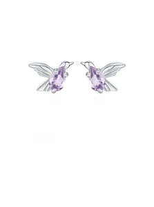 Detailed macro of bird stud earrings featuring pear-cut purple gemstones in 925 silver