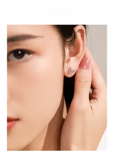 Macro shot of silver swallow stud earring with lavender gemstone on model's ear