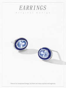 Detail view of oval silver earrings with light blue zircon and dark blue enamel frame