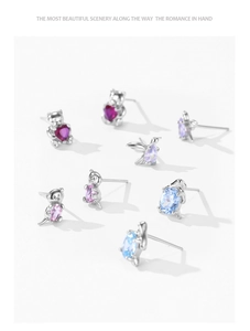 Detailed view of silver bear and bird stud earrings with colorful heart-shaped zircons
