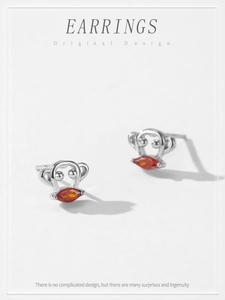 Detailed macro view of S925 silver monkey studs with sparkling orange zircon stones