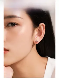 Close-up of model wearing small S925 silver stud earring with a central red gemstone