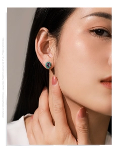 Gros plan d'une boucle d'oreille améthyste en goutte avec émail vert sur un mannequin