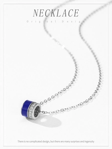 Macro detail of silver cylinder pendant with blue enamel and pavé-set zircons on a thin chain