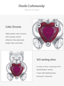Détail macro d'une boucle d'oreille ours en argent 925 avec un zircon rouge en cœur