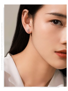 Close-up of cute silver koala stud earring with pink gemstone on a model's ear