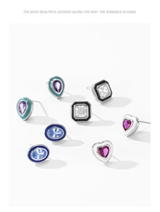 Close-up of 925 silver heart and oval stud earrings with colorful gemstones and enamel