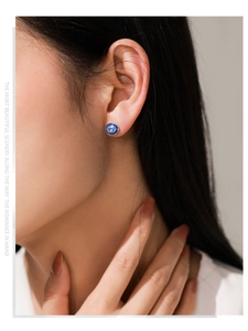 Detail of silver stud earring with oval blue zircon and enamel on a female model's ear