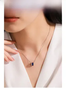 Detail of silver S925 necklace with blue enamel pendant worn on woman neckline
