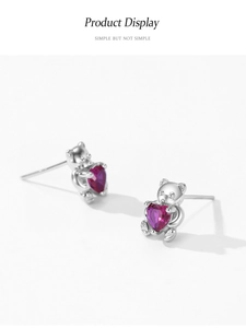 Détail de boucles d'oreilles ours en argent 925 avec un zircon rouge en forme de cœur
