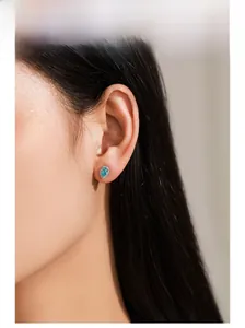 Detailopname van een zilveren zeemeermin oorbel met blauwe zirkoon op een model