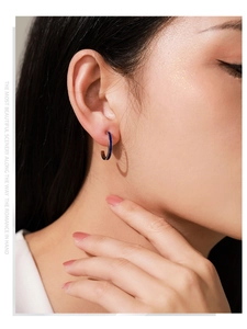 Close-up of royal blue enamel C-shape silver earrings on model with elegant side view