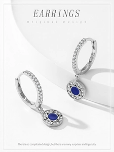 Detail of 925 silver hoop earrings with blue starburst charms and sparkling zircon stones