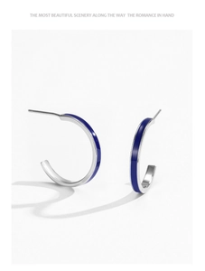 Detail of 925 sterling silver C-shaped earrings with deep sapphire blue enamel inlay