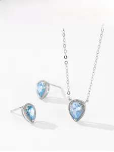 Macro shot of 925 silver necklace and teardrop earrings with blue gemstones