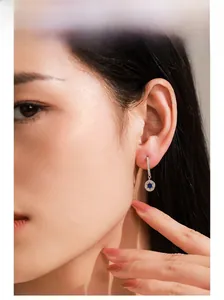 Close-up of 925 silver hoop earrings with blue stone star pendant on female model